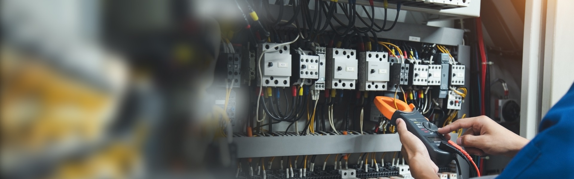 Elektriker führt Messungen mit einem Multimeter durch, um den Strom im Bedienfeld zu überprüfen, im Rahmen des Sicherheitskonzepts.