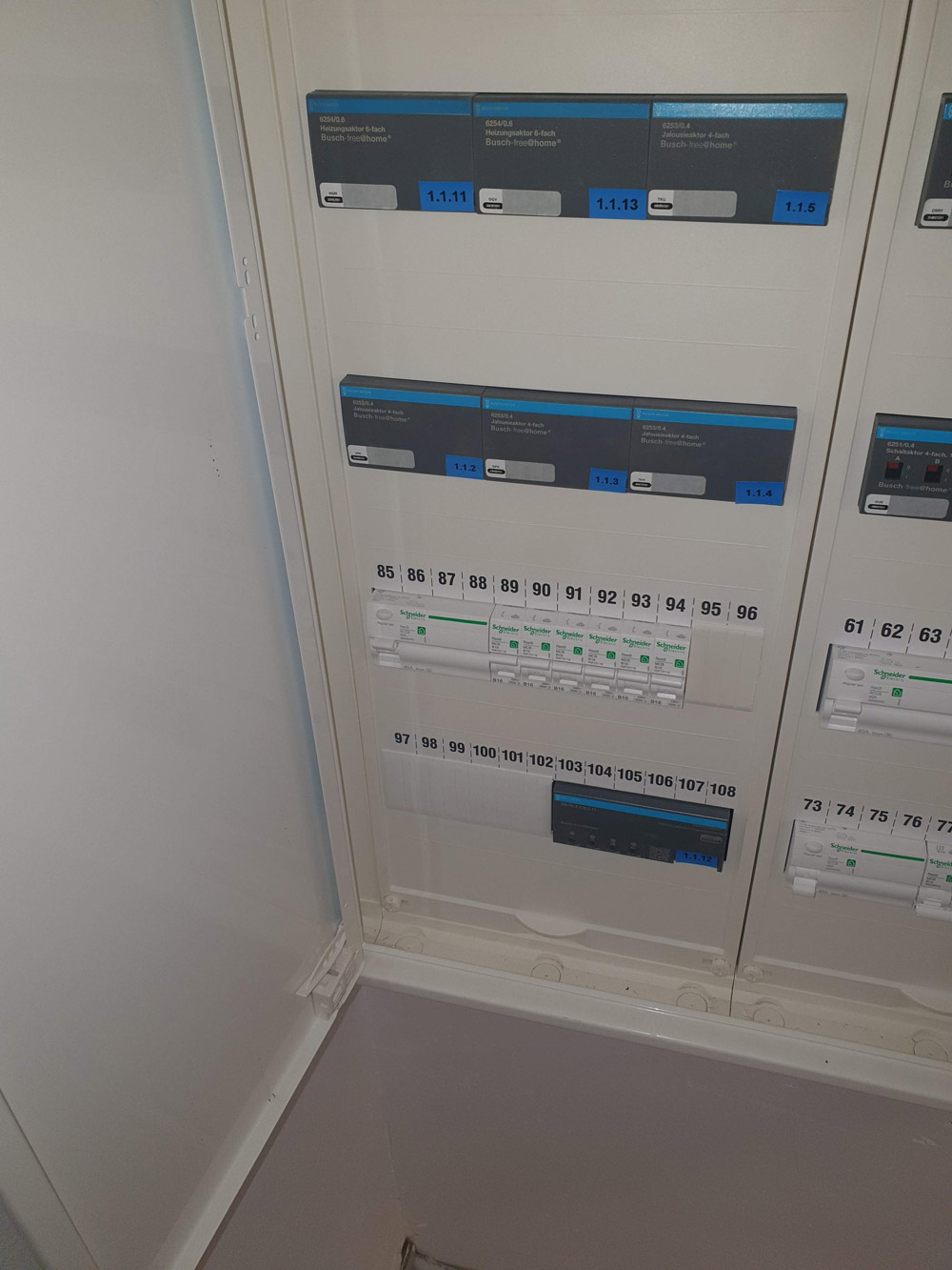 Ein geöffneter Sicherungskasten mit mehreren blauen Schaltern und nummerierten Leitungen