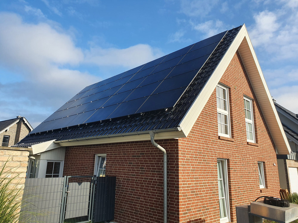 Ein rotes Backsteinhaus mit großen dunklen Solarpaneelen auf dem Schrägdach
